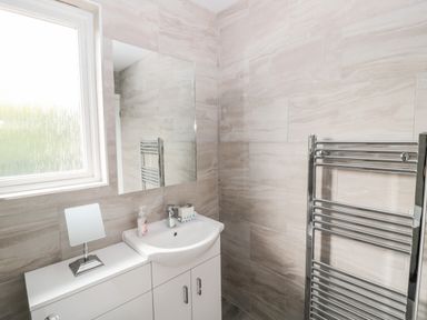 A bathroom with a sink cabinet a mirror a small mirror on the cabinet and a towel warmer at Sea View Lodge Eastfield Hall near Warkworth
