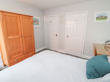 A bedroom with a wooden wardrobe two white doors a desk with a chair and framed pictures on the walls at Sea View Lodge Eastfield Hall near Warkworth