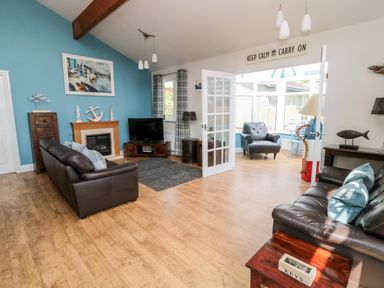 A living room with two leather sofas a fireplace and a television at Sea View Lodge in Eastfield Hall near Warkworth