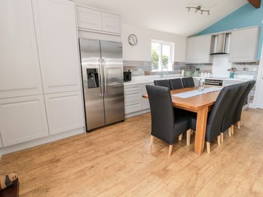 A kitchen with a wooden dining table and black chairs near a stainless steel refrigerator at Sea View Lodge in Eastfield Hall near Warkworth