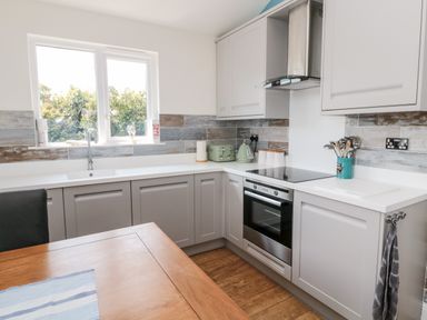 A kitchen with grey cabinets and a wooden table at Sea View Lodge Eastfield Hall near Warkworth