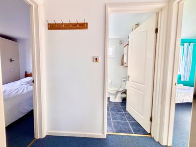 A hallway with three doorways leading to bedrooms and a bathroom at Trevone - Chalet 130 in St Merryn near Padstow