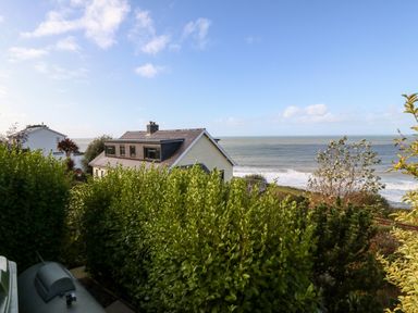 A house with a sloped roof surrounded by hedges near the sea at Machlud Haul in Llwyngwril