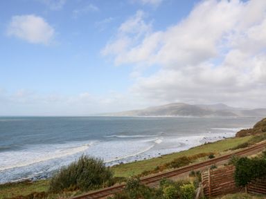 A coastal view with sea waves railway tracks and hills at Machlud Haul in Llwyngwril