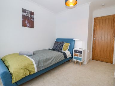 A bedroom with a single bed and multicolored chest of drawers at Machlud Haul in Llwyngwril
