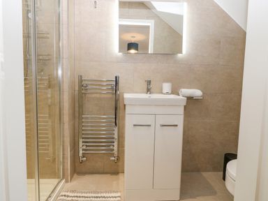 A bathroom with a sink cabinet mirror towel warmer and shower at Machlud Haul in Llwyngwril