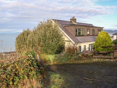 A house near the coast with bushes and a wooden fence at Machlud Haul in Llwyngwril