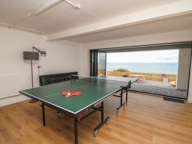 A game room with a ping pong table and paddles overlooking a sea view at Machlud Haul in Llwyngwril
