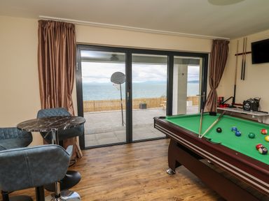 A games room with a pool table and seating area overlooking a sea view at Machlud Haul in Llwyngwril