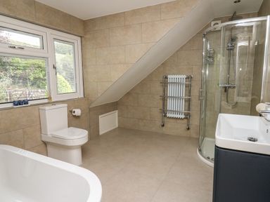 A bathroom with a toilet bathtub sink and glass shower enclosure at Machlud Haul in Llwyngwril