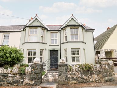 The front exterior of a semi detached house with bay windows and a stone wall at Dolwern in Dinas Cross