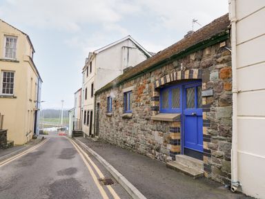 A narrow street with stone buildings and a blue door overlooking a river at Llys-Yr-Onnen in Carmarthen