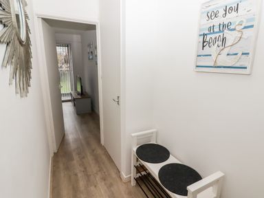 A hallway with a bench and a wall sign that says see you at the beach at 17 Coedrath Park Saundersfoot