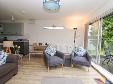 A living room with two armchairs and a sliding glass door opening to a balcony at 17 Coedrath Park in Saundersfoot