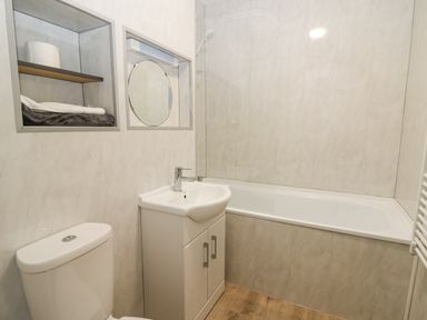 A bathroom with a toilet sink and bathtub with a shower at 17 Coedrath Park in Saundersfoot