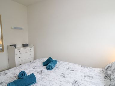 A bedroom with a bed with animal print bedding and rolled towels on top and a white chest of drawers against the wall at 28 Coedrath Park in Saundersfoot