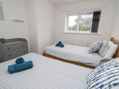 A bedroom with two single beds with striped bedding and blue towels on each at 28 Coedrath Park in Saundersfoot