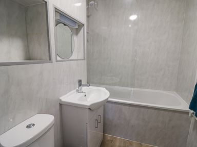 A bathroom with a toilet sink with cabinet bathtub and wall niches at 28 Coedrath Park Saundersfoot