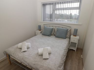 A bedroom with a bed with pillows and towels and two bedside tables with lamps at 26 Coedrath Park in Saundersfoot