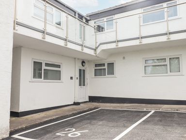 A white exterior building with multiple windows a white door and parking spaces marked on the ground at 26 Coedrath Park in Saundersfoot