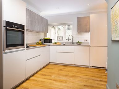A kitchen with white cabinets wooden floor a microwave and an oven at Bellman Cottage in Bowness-On-Windermere