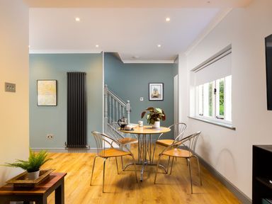 A dining area with a round table and four chairs near a window at Bellman Cottage in Bowness-On-Windermere