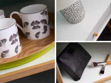 A white table with black floral patterned mugs a patterned container and makeup brushes next to a black pouch at Bellman Cottage in Bowness-On-Windermere