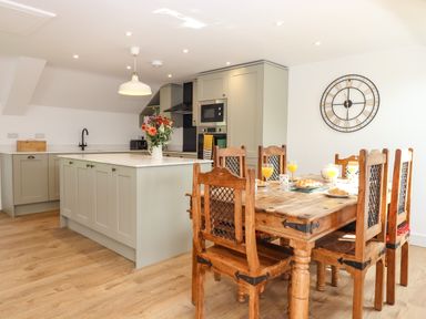 A kitchen with an island and wooden dining table with six chairs at Bumblebee Cottage in East Nynehead near Bradford-On-Tone