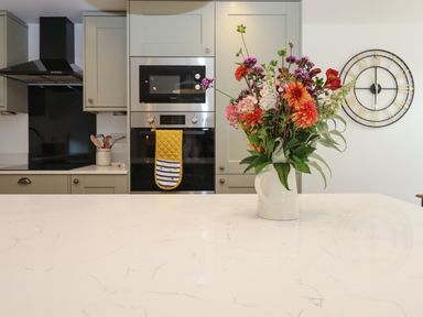 A modern kitchen with a bouquet of flowers on a marble countertop at Bumblebee Cottage in East Nynehead near Bradford-On-Tone