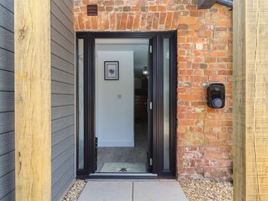 A front door entrance with a welcome mat and brick wall at Bumblebee Cottage in East Nynehead near Bradford-On-Tone