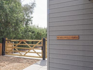 A wooden gate labeled Havilands Farm next to a gray wall with a sign reading Bumblebee Cottage at East Nynehead near Bradford-On-Tone
