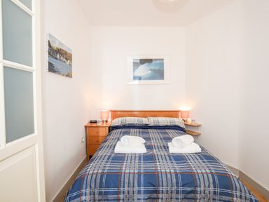 A bedroom with a double bed plaid bedding and two bedside tables with lamps at Gwel Y Mor in Pwllheli