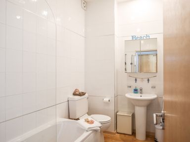 A bathroom with a bathtub toilet and pedestal sink at Gwel Y Mor in Pwllheli