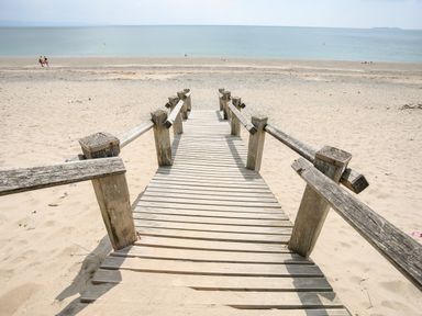 A wooden walkway leading to a sandy beach with ocean in the background at Gwel Y Mor in Pwllheli