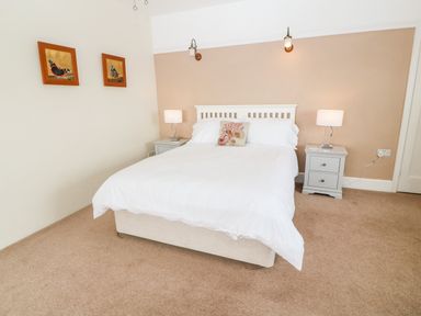 A bedroom with a double bed white bedding two bedside tables with lamps and butterfly pictures on the wall at Penmarth House in Coverack