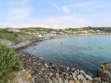 A coastal village with rocky shore and kayakers on the sea at Penmarth House in Coverack