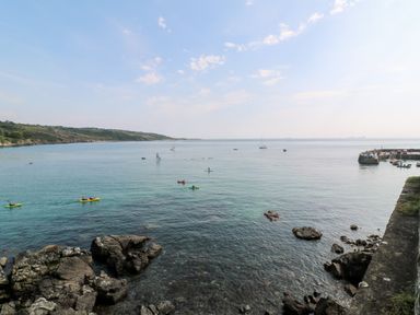 A coastal view with kayakers and sailboats on the water at Penmarth House in Coverack