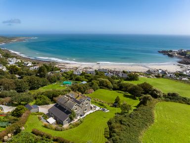 A coastal view with a house on a green land near the beach at Penmarth House in Coverack