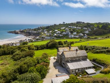 A stone house surrounded by green fields and bushes near a coastal village and beach at Penmarth House in Coverack