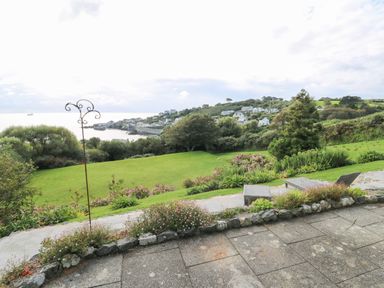 A garden with lawn and plants overlooking a coastal village and sea at Penmarth House in Coverack
