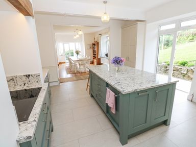 A kitchen with an island and dining area with table and chairs at Penmarth House in Coverack