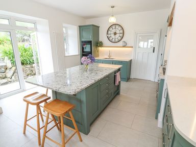 A kitchen with a large island and two wooden stools at Penmarth House in Coverack
