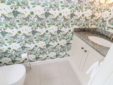 A bathroom with a toilet and white cabinet with a granite countertop and a towel rack at Penmarth House in Coverack