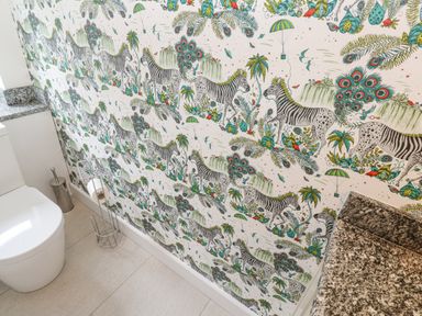 A bathroom with patterned wallpaper featuring zebras birds and plants near a toilet and granite countertop at Penmarth House in Coverack