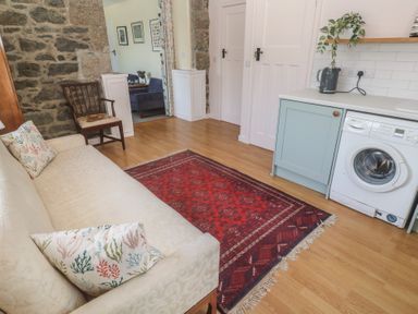 A living room with a sofa and washing machine at Penmarth House Coverack