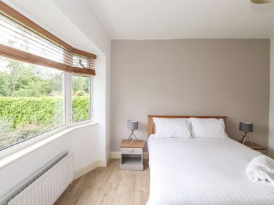 A bedroom with a double bed with white linens and two bedside tables with lamps at Halewood in Bowness-On-Windermere