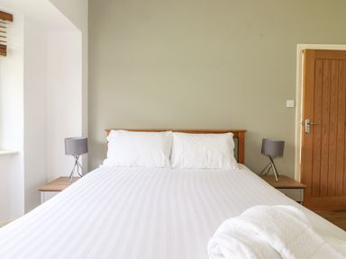 A bedroom with a double bed white linens and two bedside tables with lamps at Halewood in Bowness-On-Windermere