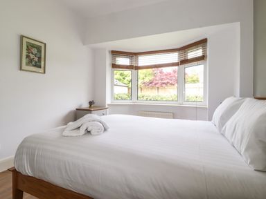 A bedroom with a large bed white bedding and a window with wooden blinds at Halewood in Bowness-On-Windermere