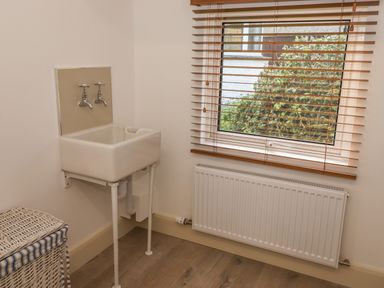 A utility room with a wall-mounted sink radiator and a window with blinds at Halewood in Bowness-On-Windermere