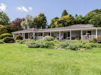 A house with a porch surrounded by plants and trees at The River House Avon Valley Stonehenge with fishing Salisbury